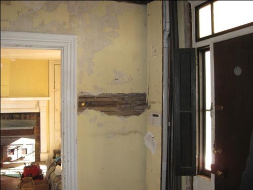 photo of lath exposed in foyer wall where the plaster has deteriorated