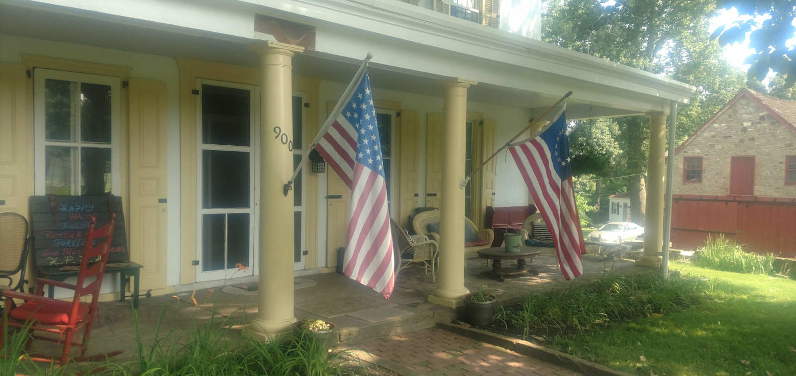 photo of front porch on Penrose Strawbridge farmhouse with colonial and modern US flags