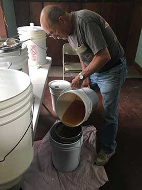 photo of Pete Choate pouring honey through a filter